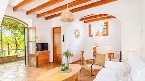 A spacious living area with a wooden ceiling, a dining table, a sofa, and a TV. - Holiday Home 'Ca N'Antonia' citrus farm stay (Sóller)