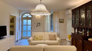 Ein Wohnzimmer mit einer Couch, einem Fernseher, einem dekorativen Schrank und einer Tür zu einem anderen Raum.