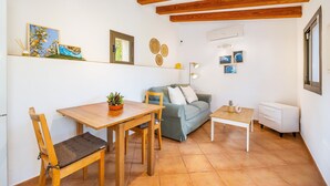 Una sala de estar acogedora con una mesa de comedor de madera, un sofá y una mesita blanca.