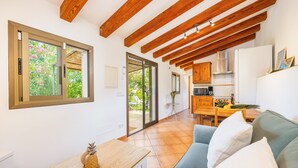 Una cocina moderna con vigas de madera, un comedor con mesa y sillas, y una sala de estar con sofá.