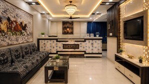 A modern reception area with a chandelier, a reception desk, a sofa, and a TV. - Hotel Apollo SpRing Road Odhav Ahemdabad (Ahmedabad)