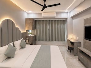 Une chambre d’hôtel moderne équipée d’un lit, d’un bureau, d’une chaise et d’un ventilateur de plafond.