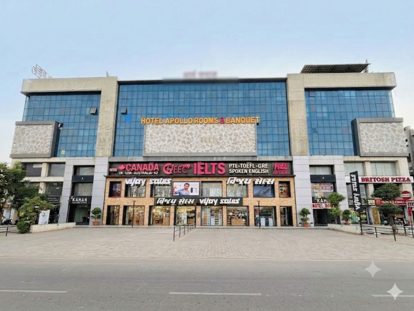 A hotel with a modern facade, a sign for Canada IELTS, and a British Pizza restaurant.