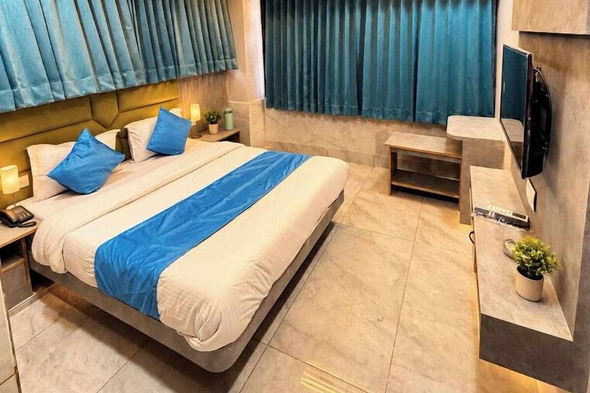 Ein modernes Hotelzimmer mit einem großen Bett, einem Schreibtisch, einem Fernseher und einer Klimaanlage.