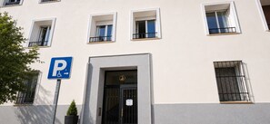 A building with a parking sign, a gated entrance, and multiple windows. - Retiro V (Madrid)