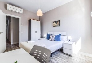 A modern hotel room with a bed, bedside table, and a desk with a chair. - Retiro V (Madrid)