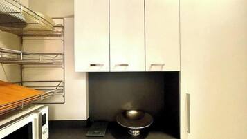 Una cucina con mobili bianchi, un forno a microonde e un piano cottura nero.