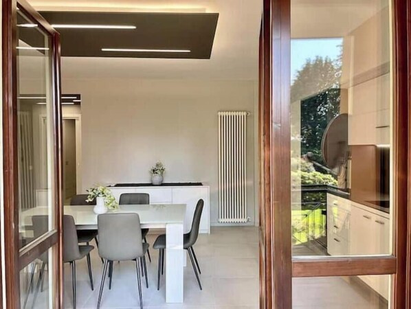 A modern kitchen with a dining area, a radiator, and a view of the outdoors. - Elegant modern apartment with pool and panoramic balconies (Stresa)
