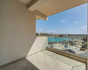 A balcony with a clear view of a coastal area, including a marina and buildings. - A Stylish 2BR seafront home in Qawra w/WIFI & AC (San Pawl il-Baħar)