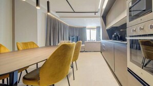 A modern kitchen with a wooden dining table, yellow chairs, and built-in appliances. - Seafront Seafront 3BR home in Qawra w/WIFI & AC (San Pawl il-Baħar)