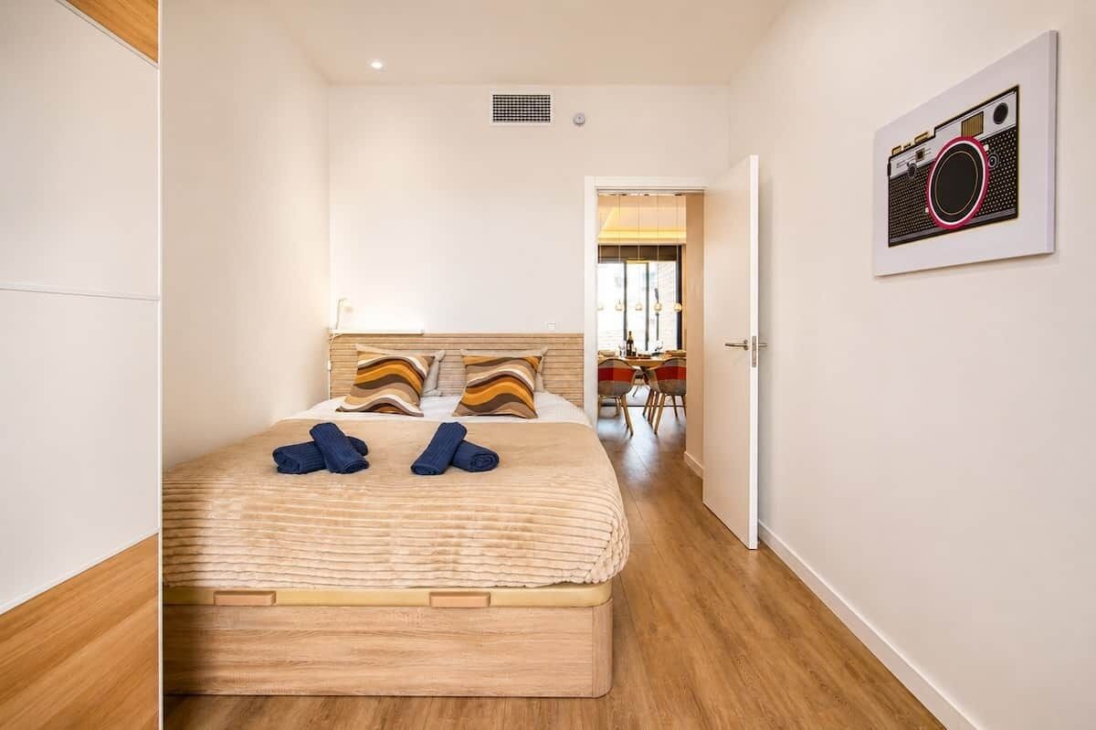 Une chambre à coucher avec un lit, des oreillers et un tableau accroché au mur.