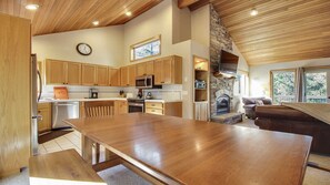 A spacious kitchen with wooden cabinets, a dining table, and a stone fireplace. - 20 East Butte-Sunriver, Oregon: Hot Tub, BBQ, WiFi, SHARC Aquatics, Tubing Hill, Mt. Bachelor, Golf, Deschutes River, Tennis, Bike Paths (Sunriver)