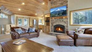 Ein gemütliches Wohnzimmer mit Ledersofas, einem Kamin und einem großen Fernseher.