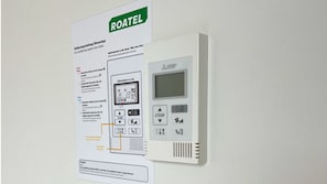 En ROATEL-kontrollpanel för luftkonditionering med en digital display och olika knappar för att justera temperatur och fläkthastighet.