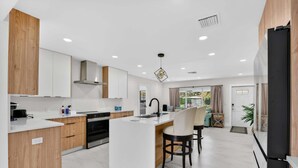 Une cuisine moderne dotée d’un îlot central, de meubles en bois et d’un coin repas avec deux chaises.