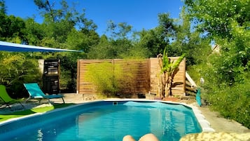 Une piscine entourée d’une clôture en bois, avec une chaise et une plante à proximité.
