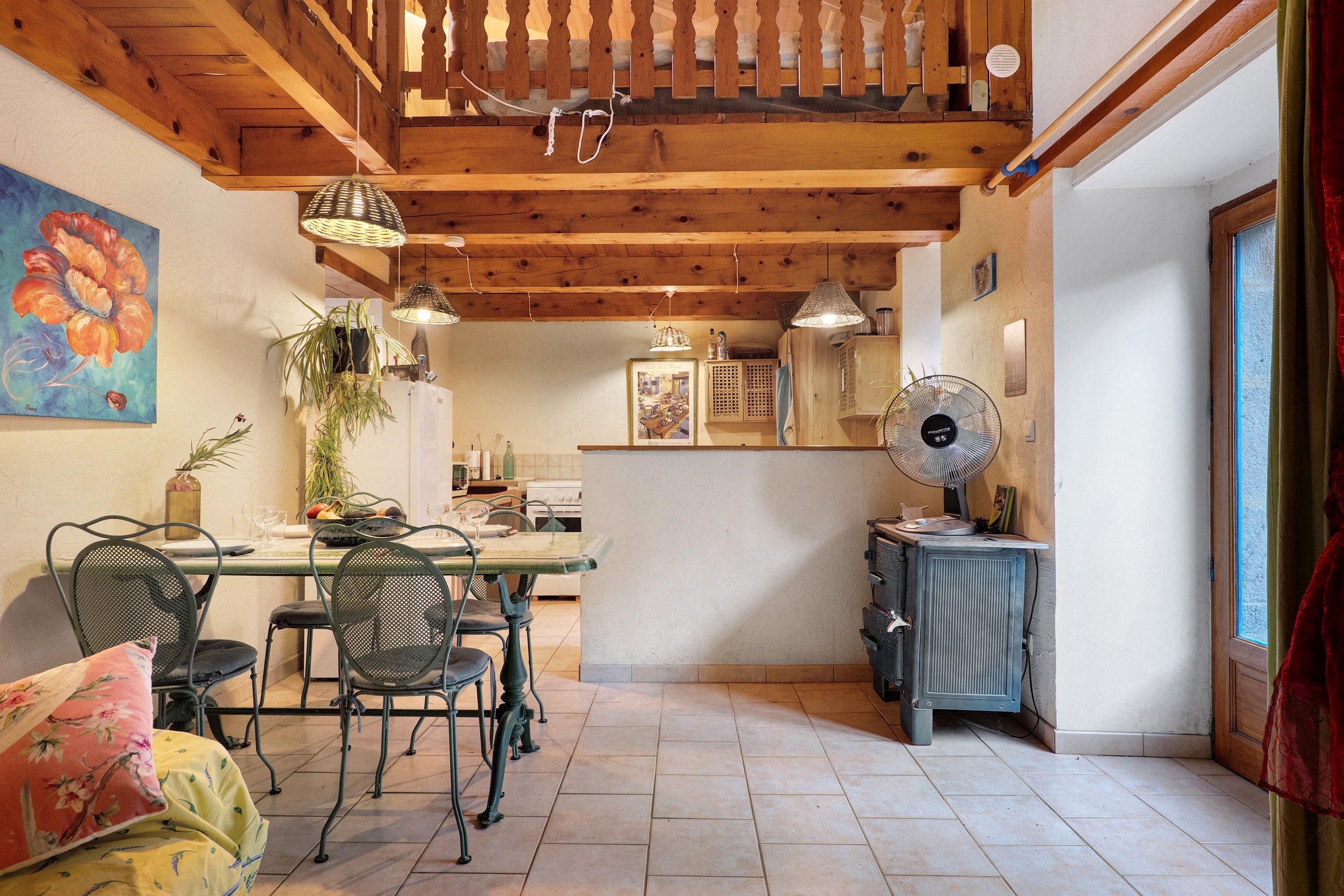 Cocina rústica con vigas de madera, una mesa de comedor con sillas, un radiador y una ventana.