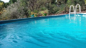 A clear blue pool with a white ladder, surrounded by lush greenery and potted plants. - Holiday Home 'La Fée Du Val - Cottage in Ardèche' with Private Pool, Wi-Fi and Air Conditioning (Rosières)