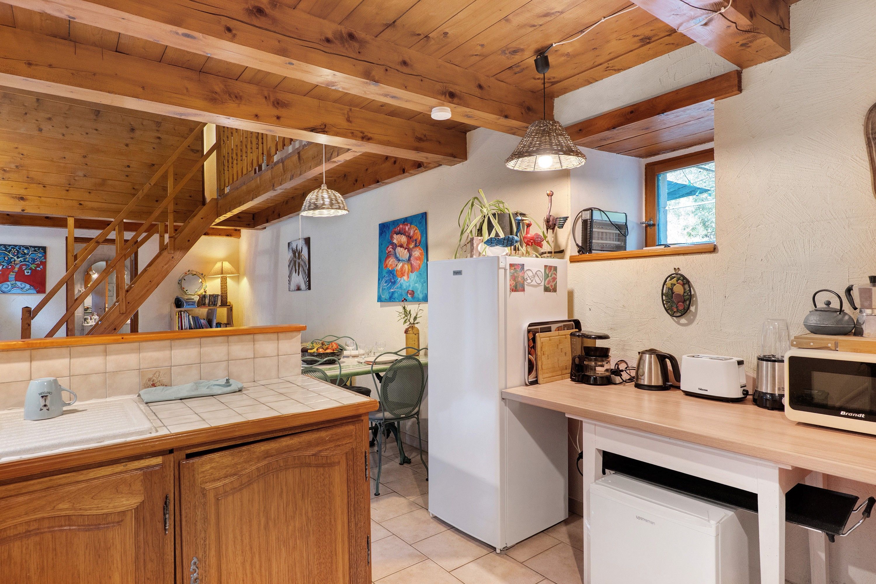 A kitchen with wooden beams, a refrigerator, a sink, a stove, and various kitchen appliances.