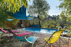 A swimming pool with lounge chairs and a shaded area. - Holiday Home 'La Fée Du Val - Cottage in Ardèche' with Private Pool, Wi-Fi and Air Conditioning (Rosières)