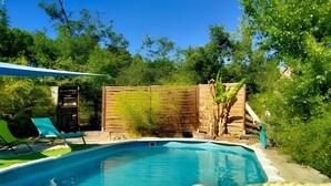 A swimming pool with a wooden fence, a chair, and a plant. - Holiday Home 'La Fée Du Val - Cottage in Ardèche' with Private Pool, Wi-Fi and Air Conditioning (Rosières)