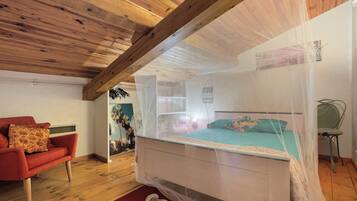 Un dormitorio con techo de madera, una cama con mosquitero, una silla roja y una silla verde.