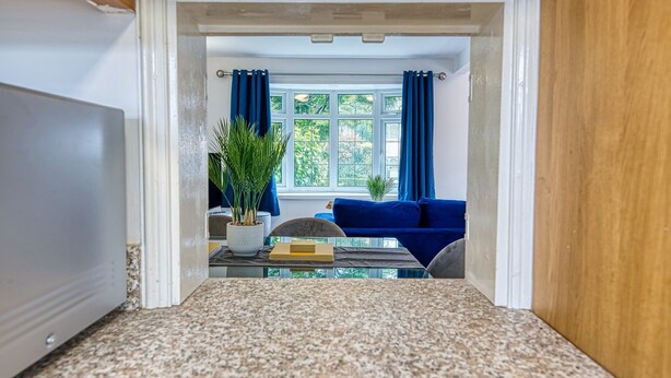 Una habitación con vistas a un sofá azul y una ventana con cortinas.