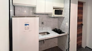A compact kitchen with white cabinets, a built-in microwave, a sink, and a refrigerator. - Atlantico 204 apartment, 50m2, 1 bedroom, sleeps up to 4 people. (Fortaleza)