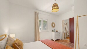 A bedroom with a bed, bedside table, lamp, window, and a view of a bathroom. - Apartment 'Monte Do Poço Country House' with Private Pool, Wi-Fi and Air Conditioning (Erra)