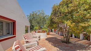 A patio with white chairs and a brick floor, surrounded by greenery and a white building. - Apartment 'Monte Do Poço Country House' with Private Pool, Wi-Fi and Air Conditioning (Erra)