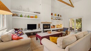 A living room with a fireplace, white walls, and a TV. - Apartment 'Monte Do Poço Country House' with Private Pool, Wi-Fi and Air Conditioning (Erra)