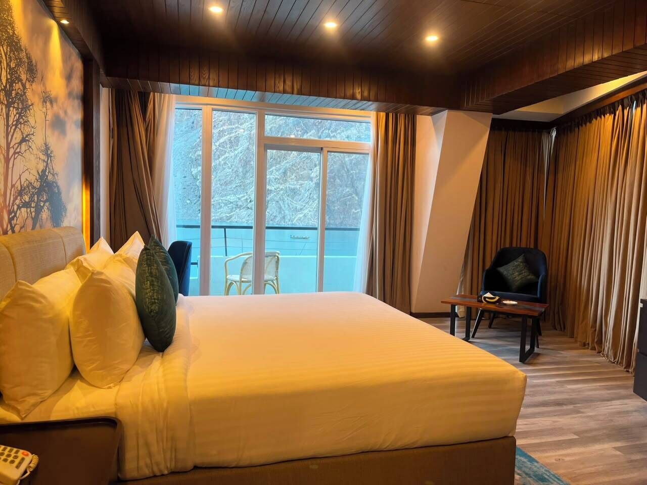 Une chambre d’hôtel avec un grand lit, une chaise, une petite table et une vue sur l’extérieur.