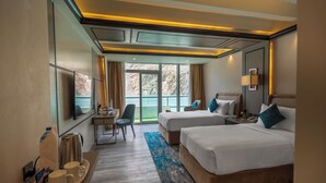 A hotel room with two beds, a desk, a chair, a TV, and a view of the outdoors. - Pearl Continental Attabad Lake (Aina Abad)