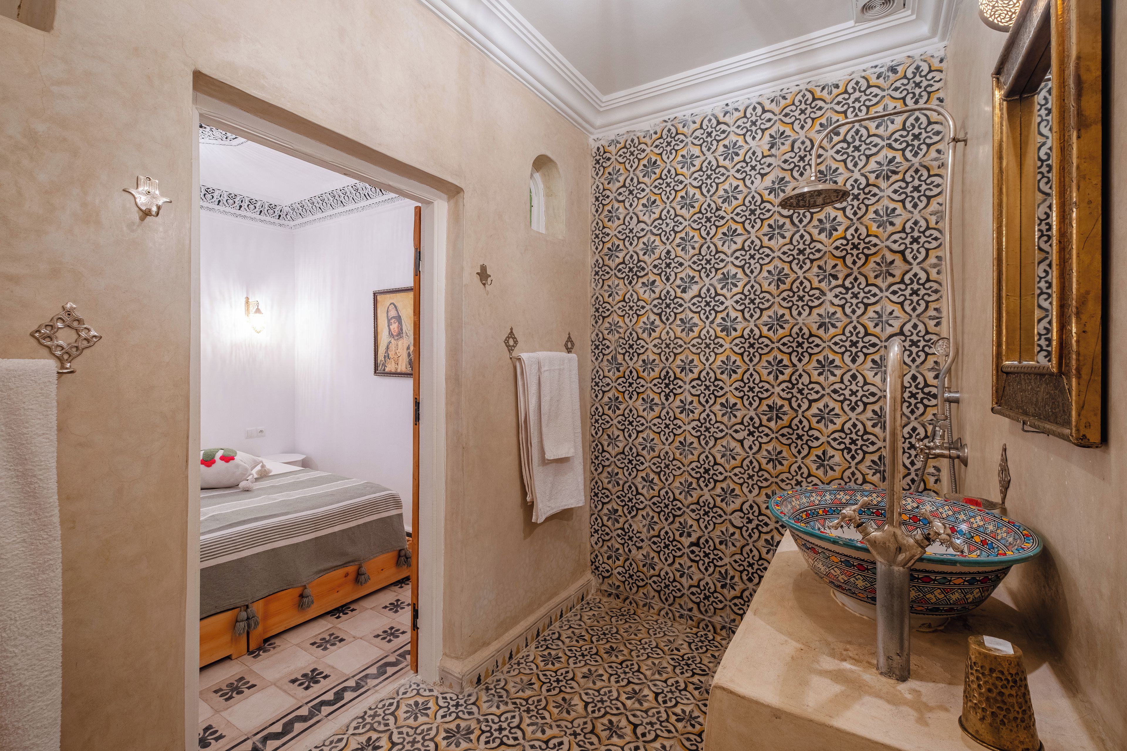 A bathroom with a patterned tile wall, a large decorative sink, and a shower.