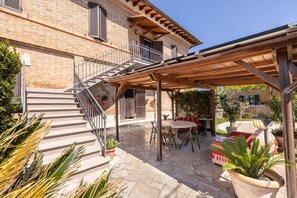 Ein Backsteinhaus mit einer Treppe, die zu einer überdachten Terrasse führt.
