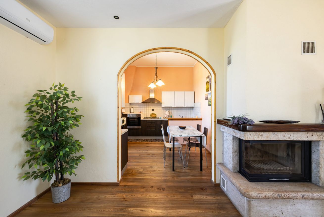 Una cocina con un arco que da a un comedor, una planta en maceta y una chimenea.