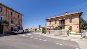 A street with a white van parked on the side, a stop sign, and a building with a balcony. - This two-level apartment located in a semi-detached house in the center of Arbia, just a 5-minute drive from Siena, is the ideal starting point for visiting the Crete Senesi, Chianti, and Val d'Orcia. Featuring a parking space, a shared garden with a pat (Arbia)