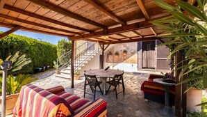 An outdoor patio with a wooden pergola, a round table with chairs, a sofa, and a small table with a plant. - This two-level apartment located in a semi-detached house in the center of Arbia, just a 5-minute drive from Siena, is the ideal starting point for visiting the Crete Senesi, Chianti, and Val d'Orcia. Featuring a parking space, a shared garden with a pat (Arbia)