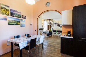 Ein Essbereich mit Tisch und Stühlen, eine Küche mit Schränken und eine Wohnbereich mit Sofa und Treppe.