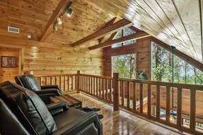 Eine Holzhütte mit Veranda, Ledersitzgelegenheiten und Blick ins Freie.