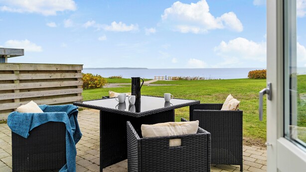Un espace extérieur aménagé avec des meubles en osier, une table et une vue sur la mer.