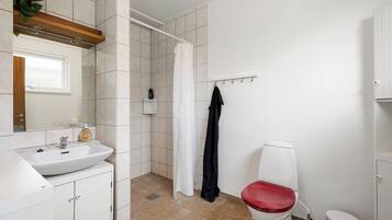 A bathroom with a white sink, a red toilet, a shower curtain, and a towel rack.