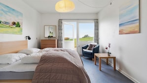 Une chambre à coucher avec un lit, une chaise, une table et une fenêtre donnant sur un beau paysage.