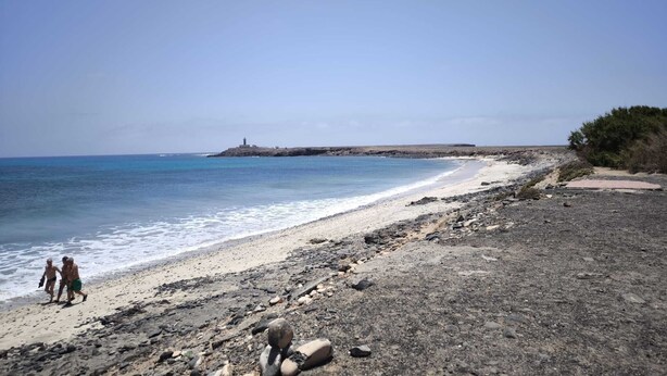 A beach with a rocky shoreline, a lighthouse in the distance, and a clear sky. - Private Beach Apartment WiFi- MorroJable- 2 Bedrooms (Morro Jable)