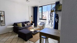 A living room with a sofa, ottoman, coffee table, and a dining table. - Private Beach Apartment WiFi- MorroJable- 2 Bedrooms (Morro Jable)