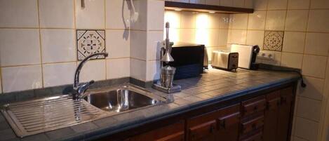 A kitchen with a sink, a coffee machine, a toaster, and a microwave.