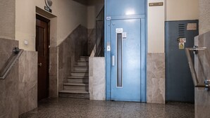 A stairwell with a blue elevator door, a marble floor, and a door labeled "BAJO". - Retiro VI (Madrid)