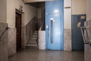 A stairwell with a blue elevator door, a marble floor, and a door labeled "BAJO". - Retiro VI (Madrid)
