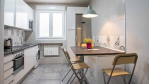 A modern kitchen with a built-in oven, microwave, and washing machine, a dining area with a table and chairs, and a pendant light. - Retiro VI (Madrid)