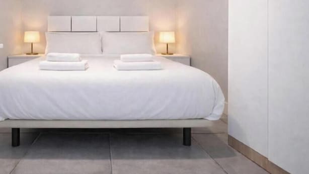 A neatly made bed with white linens and two pillows, flanked by two bedside lamps on either side. - Retiro VI (Madrid)